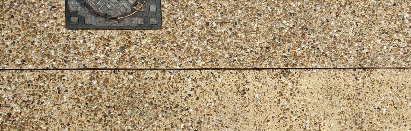 Patchy exposed aggregate concrete sandblasted at the top and untreated at the bottom